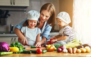 Frau mit zwei Kindern bereitet Essen zu